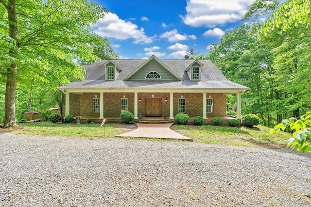 view of front of home with a porch, brick siding, and a shingled roof