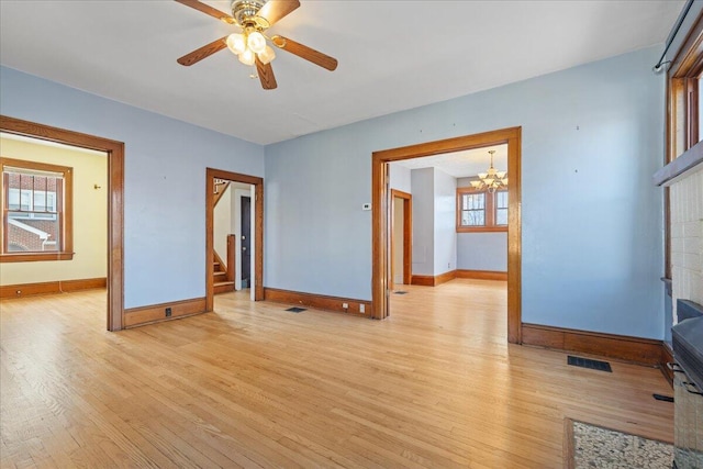 unfurnished living room with light wood finished floors, baseboards, a chandelier, and stairway