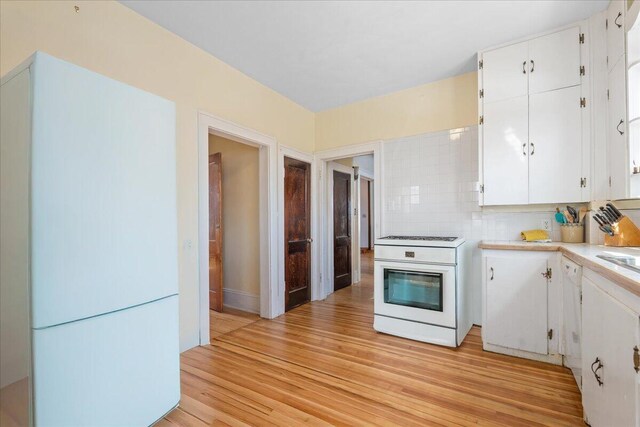 kitchen with electric stove, light wood finished floors, white cabinetry, light countertops, and decorative backsplash