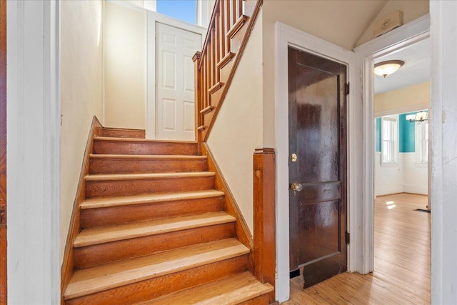 stairs featuring wood finished floors and a chandelier