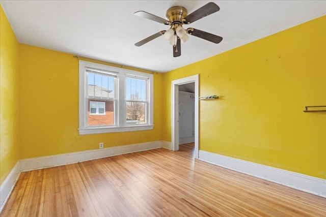 unfurnished room with baseboards, light wood-style floors, and a ceiling fan