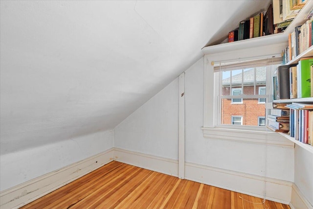 additional living space with vaulted ceiling, wood finished floors, and baseboards