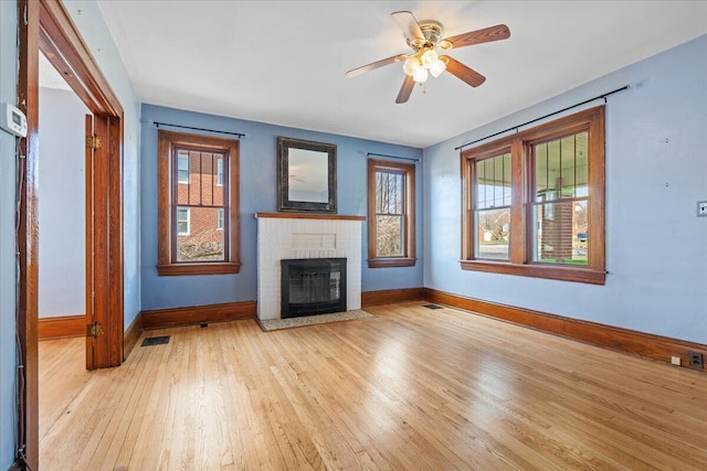 unfurnished living room with baseboards, wood finished floors, healthy amount of natural light, and a fireplace