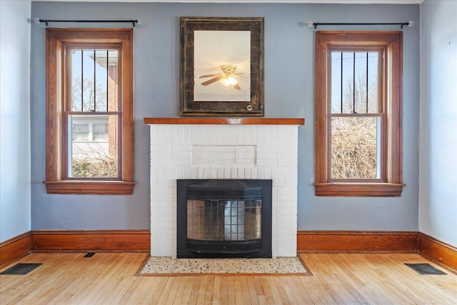 detailed view of wood finished floors, baseboards, and a brick fireplace