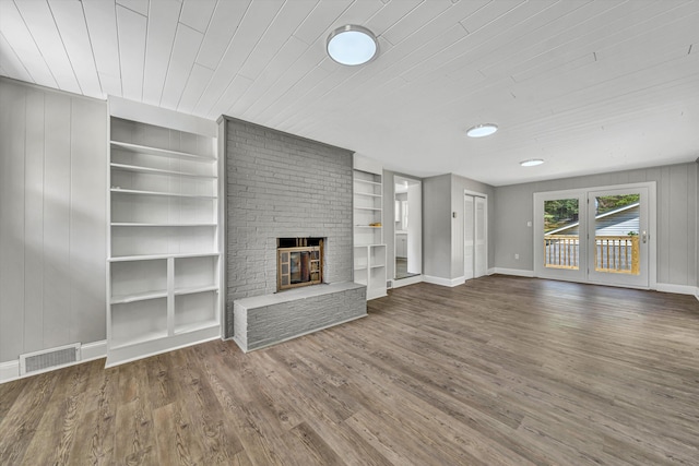unfurnished living room with wood ceiling, visible vents, wood finished floors, and built in features