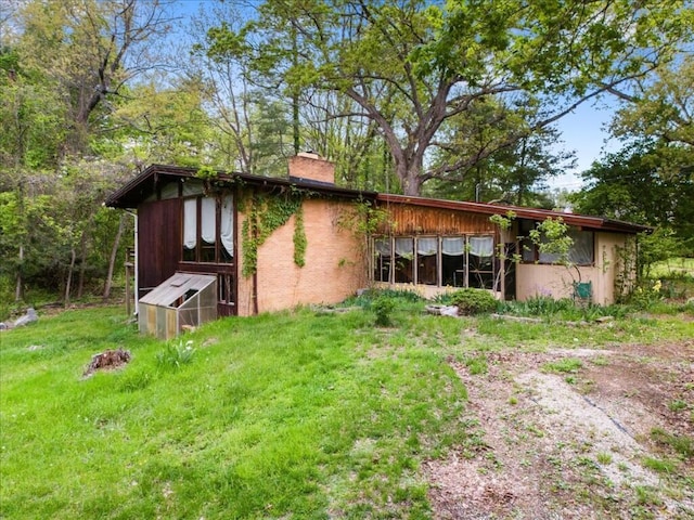 rear view of property with a chimney, an outbuilding, and exterior structure