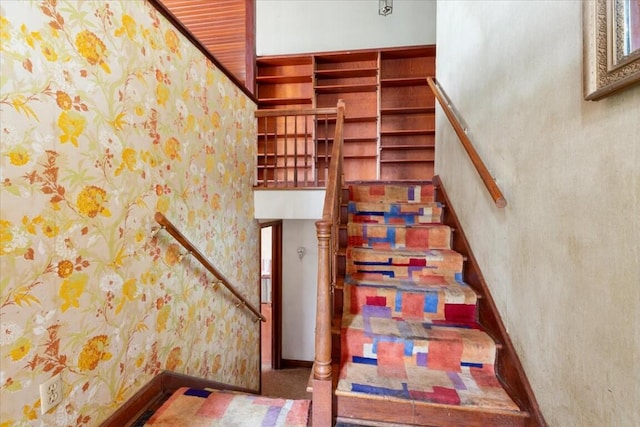 staircase featuring baseboards and a towering ceiling