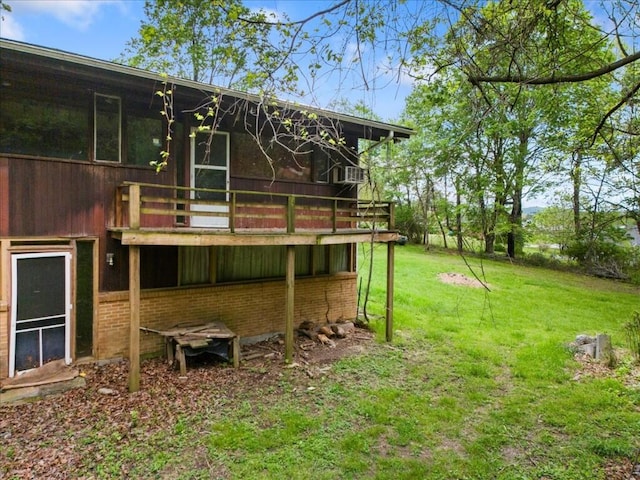 rear view of property featuring a yard, a deck, and brick siding
