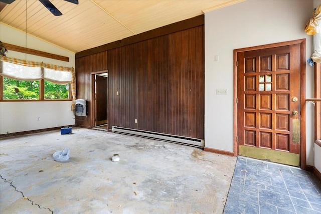 unfurnished room featuring unfinished concrete flooring, wooden walls, baseboards, a baseboard heating unit, and vaulted ceiling