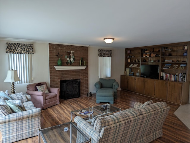 living area with crown molding, wood finished floors, and a fireplace