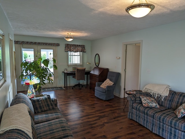 living area with baseboards, a textured ceiling, and wood finished floors