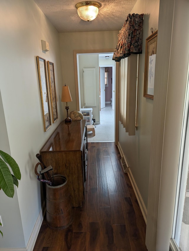 hallway with baseboards, dark wood-style flooring, and a textured ceiling