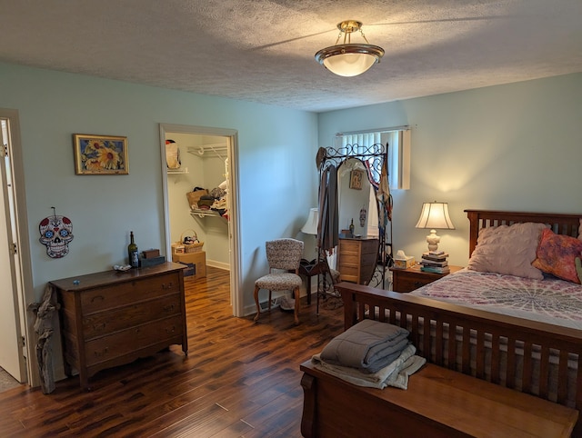 bedroom featuring dark wood-style flooring, a walk in closet, a textured ceiling, and a closet
