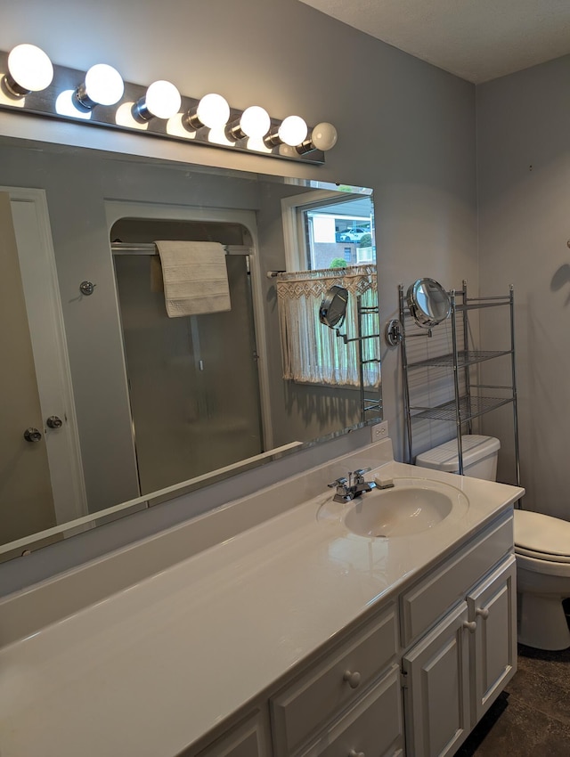 bathroom featuring an enclosed shower, toilet, and vanity