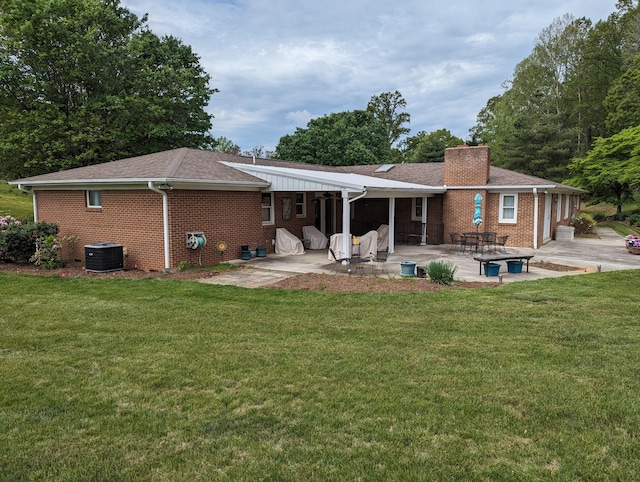 back of property featuring a lawn, a patio area, and brick siding