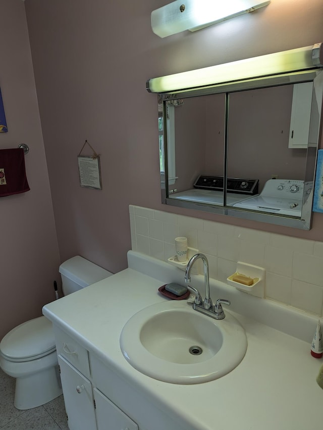 bathroom featuring toilet, tasteful backsplash, washer and dryer, and vanity