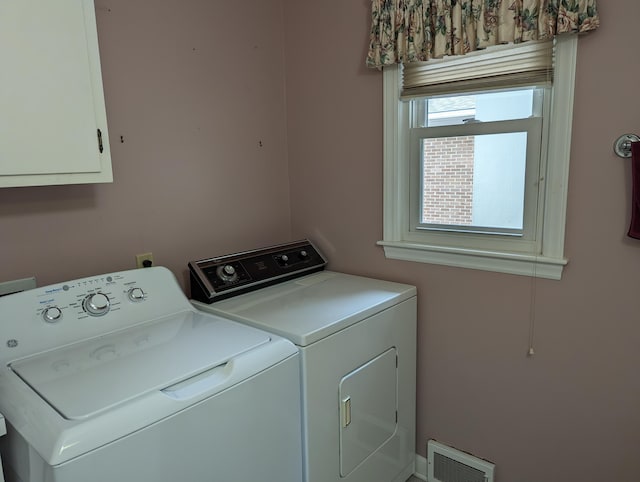 washroom with washing machine and dryer, visible vents, and cabinet space