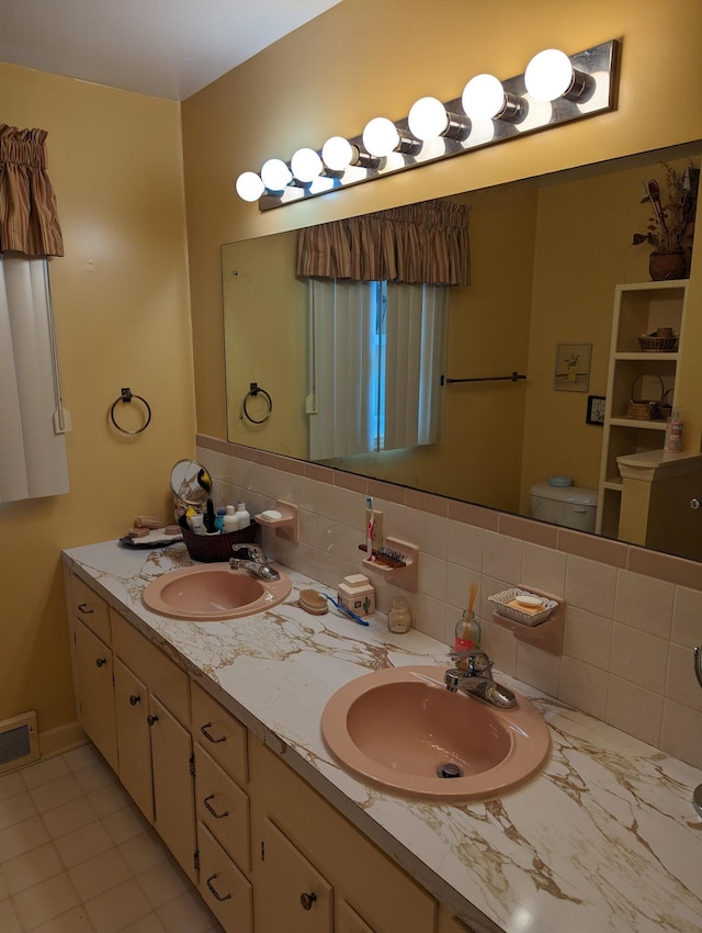 full bath with tasteful backsplash, visible vents, and a sink