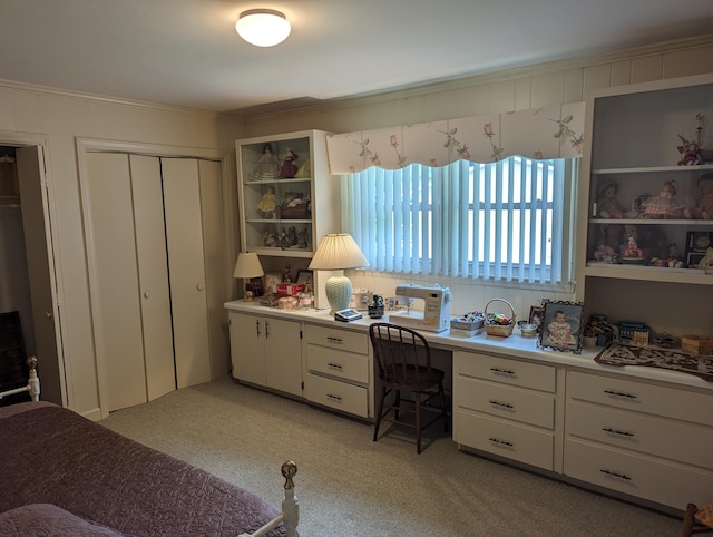 bedroom with built in desk, crown molding, light carpet, and a closet