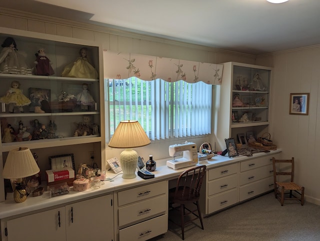 office with built in study area, crown molding, and light colored carpet