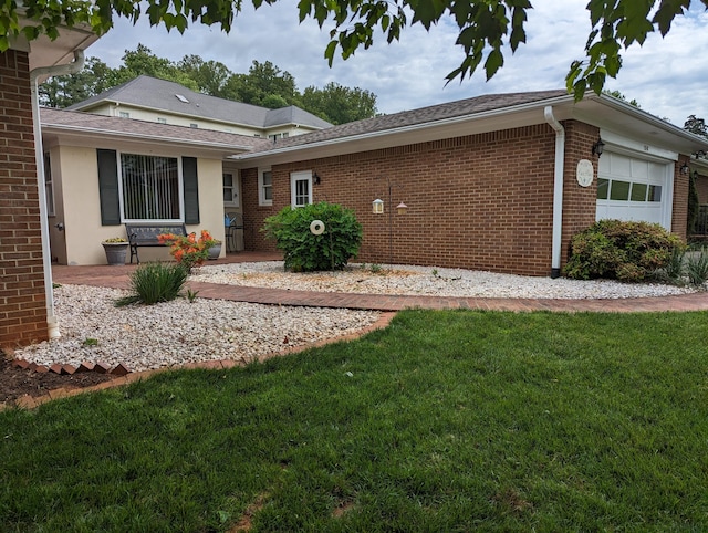 exterior space with an attached garage, a shingled roof, brick siding, and a lawn