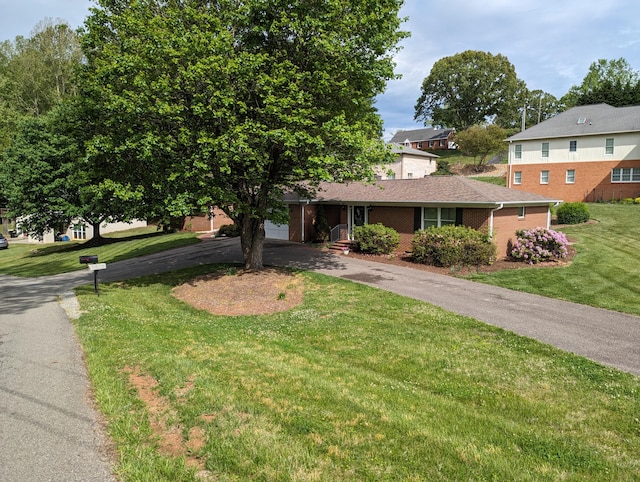 view of front of property featuring a front yard, brick siding, and driveway