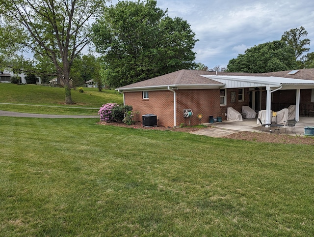 rear view of property featuring a yard, a patio area, brick siding, and central air condition unit