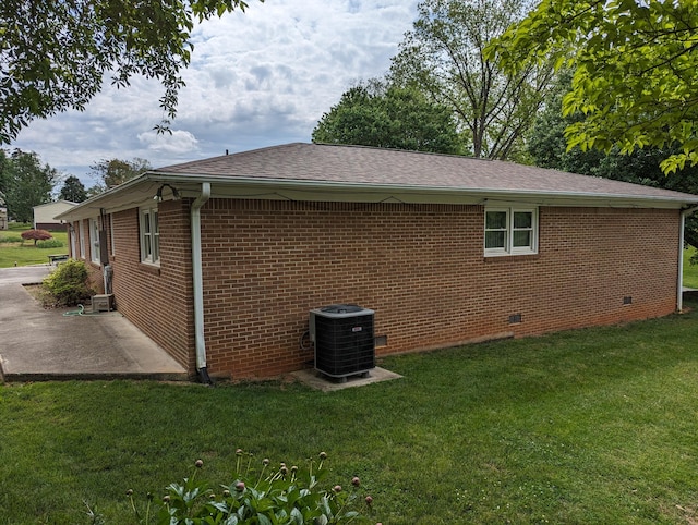 view of side of property with a lawn, brick siding, cooling unit, a patio area, and crawl space