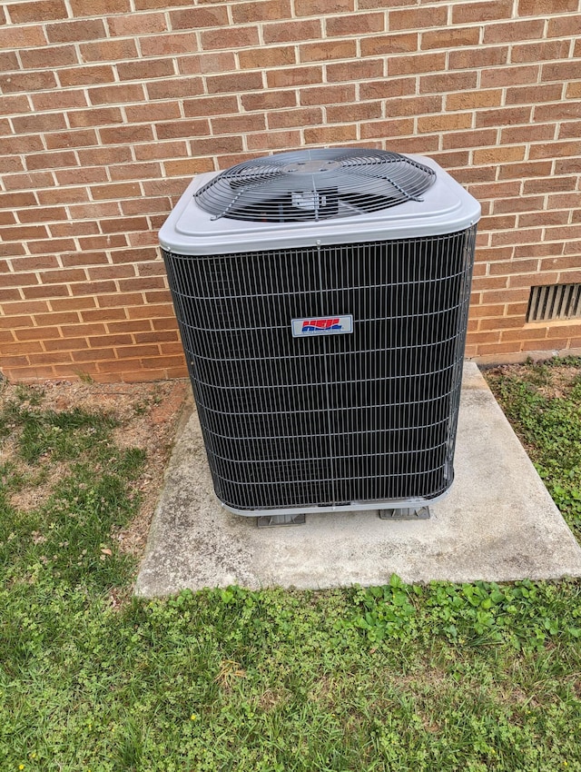 details featuring central AC, brick siding, and visible vents