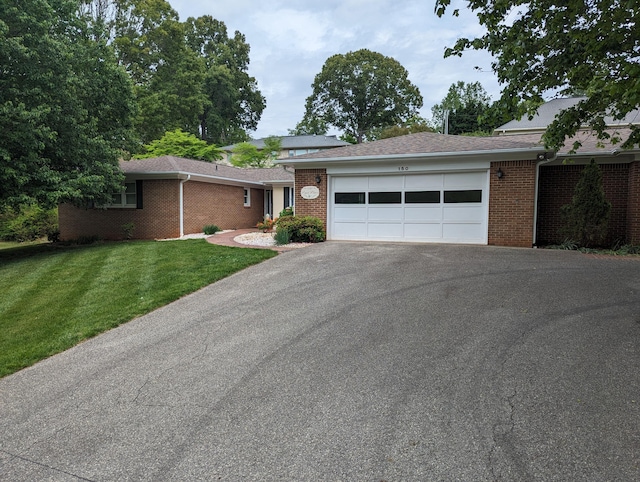 ranch-style house featuring a front yard, brick siding, driveway, and a garage