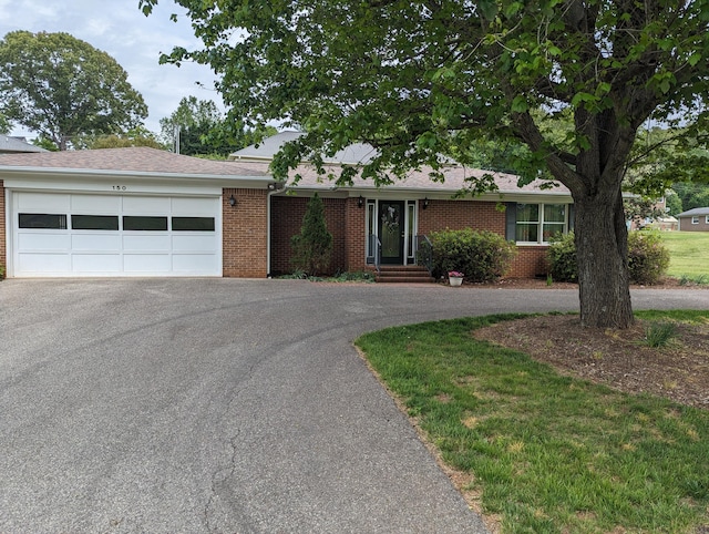 ranch-style home featuring an attached garage, brick siding, and aphalt driveway