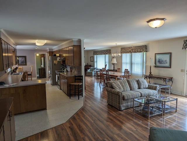 living area with ornamental molding, an inviting chandelier, and light wood-type flooring