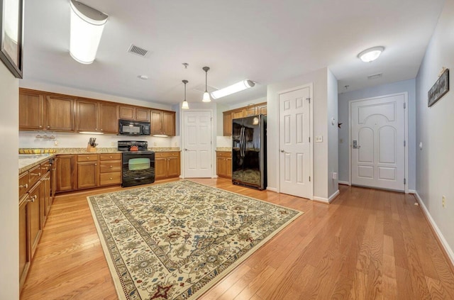 1100 Celebration Ave Unit 405, Moneta, VA 24121 - kitchen with black appliances, brown cabinets, light wood-type flooring, hanging light fixtures, and light stone countertops