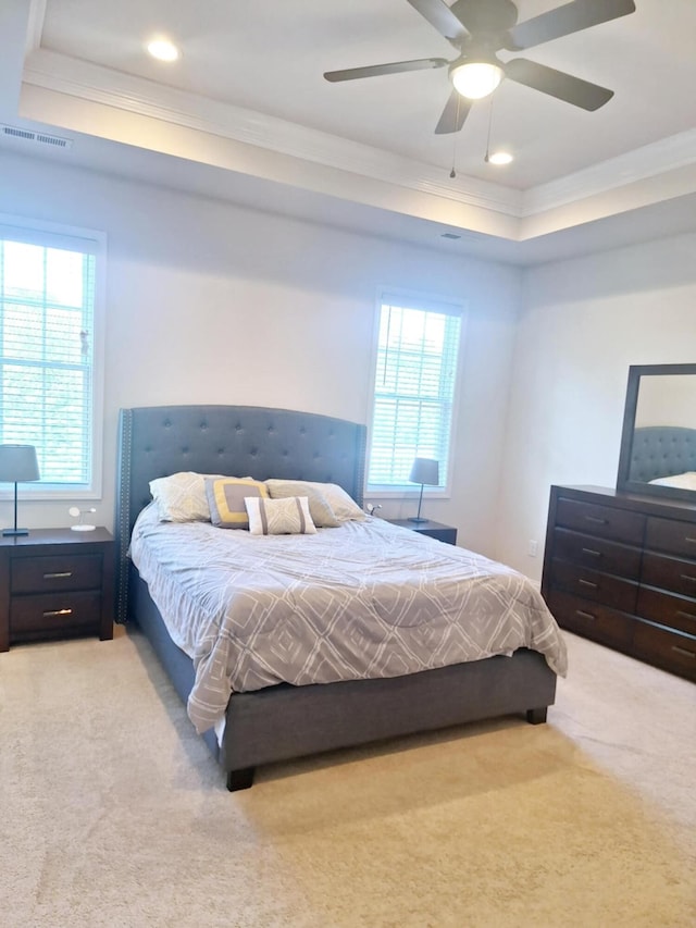 bedroom featuring crown molding, visible vents, a raised ceiling, ceiling fan, and light carpet