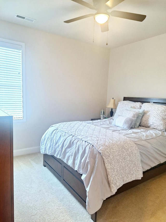 carpeted bedroom featuring baseboards, ceiling fan, and visible vents