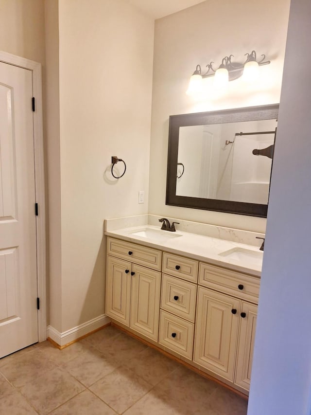 full bathroom featuring baseboards, tile patterned flooring, double vanity, and a sink
