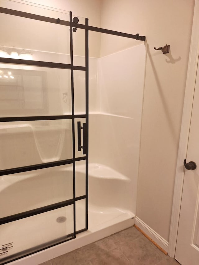 full bathroom featuring tile patterned flooring, baseboards, and a shower stall