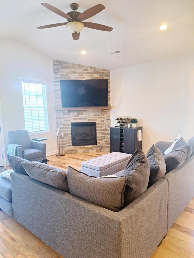 living room with wood finished floors, a fireplace, visible vents, ceiling fan, and lofted ceiling