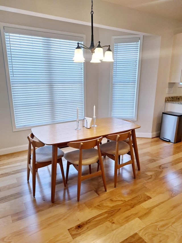 dining room with light wood-style floors, a chandelier, and baseboards