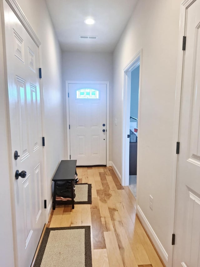 doorway to outside with baseboards, light wood finished floors, and visible vents
