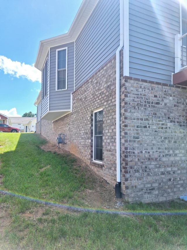 view of side of property featuring a yard and brick siding