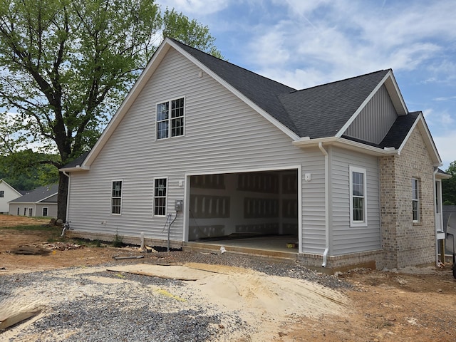 5591 Old Grove Ln, Salem, VA 24153 - view of property exterior with dirt driveway, brick siding, a shingled roof, and an attached garage