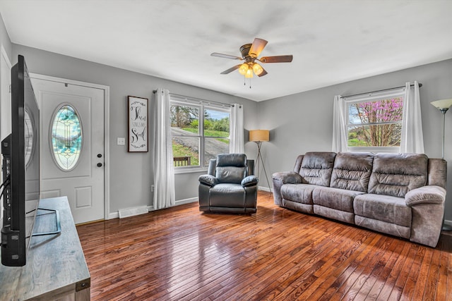 living area with baseboards, hardwood / wood-style floors, visible vents, and ceiling fan