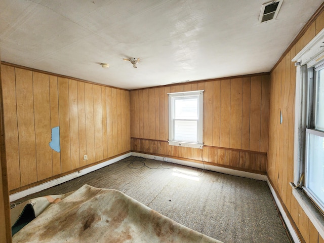 empty room featuring wood walls, baseboards, and visible vents