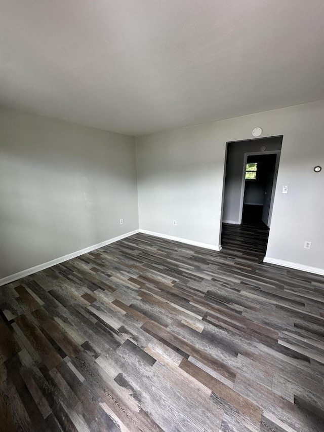 empty room featuring dark wood-style flooring and baseboards