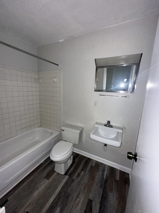 full bath featuring toilet, wood finished floors, a sink, a textured ceiling, and shower / bathtub combination