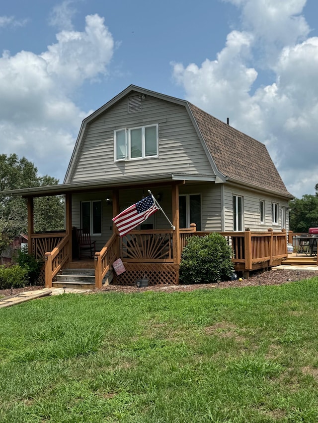 back of property with roof with shingles, a gambrel roof, and a lawn