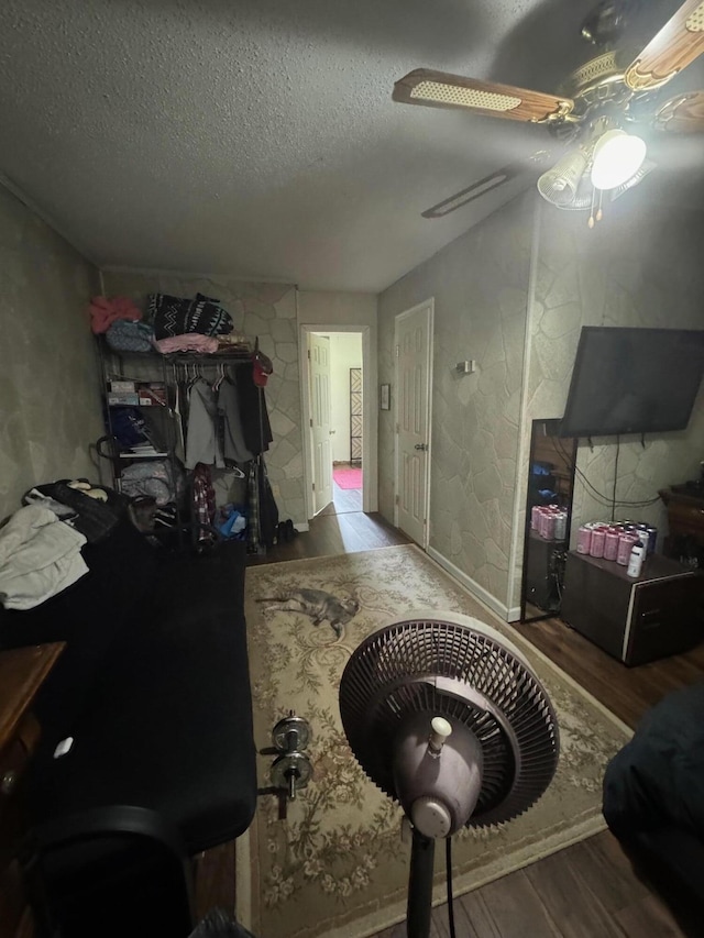 interior space featuring ceiling fan, a textured ceiling, and wood finished floors