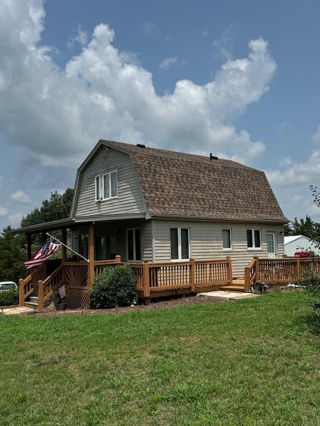 back of property featuring a yard, a deck, a shingled roof, and a gambrel roof