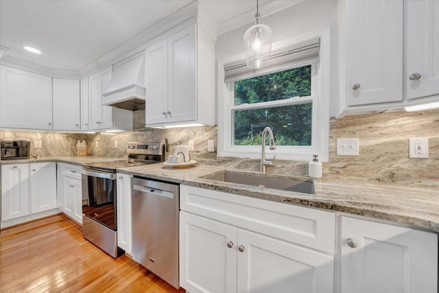 kitchen with stainless steel appliances, custom exhaust hood, a sink, white cabinets, and crown molding